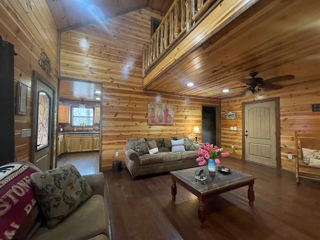 living area with dark wood-style floors, wood walls, wooden ceiling, and ceiling fan