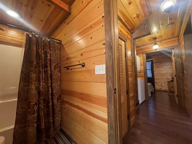 interior space featuring wood finished floors, wood walls, curtained shower, wooden ceiling, and stacked washer / dryer