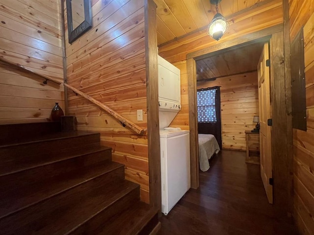 stairway with wood ceiling, wooden walls, wood finished floors, and stacked washing maching and dryer