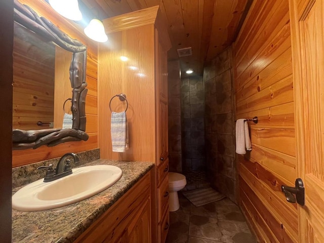 full bath featuring wood walls, wood ceiling, toilet, a tile shower, and vanity