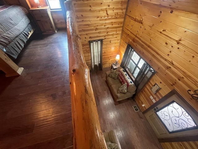 unfurnished living room with visible vents, wood walls, a high ceiling, and wood-type flooring