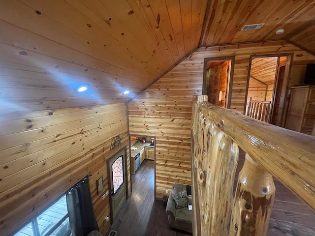 hall featuring visible vents, wood walls, vaulted ceiling, wooden ceiling, and hardwood / wood-style flooring