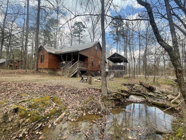 rear view of house featuring log veneer siding and a porch