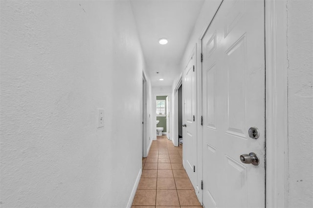 corridor featuring light tile patterned floors and baseboards