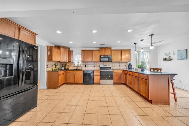 kitchen featuring black appliances, a sink, tasteful backsplash, a peninsula, and brown cabinetry