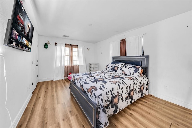 bedroom with visible vents, baseboards, and light wood finished floors