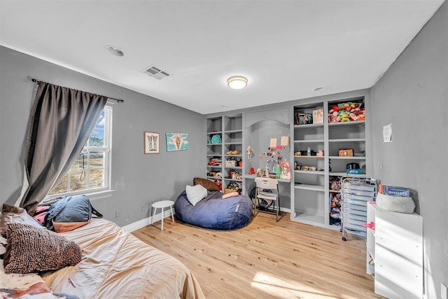 bedroom with wood finished floors, visible vents, and baseboards