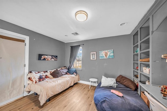 bedroom with light wood-type flooring, visible vents, and baseboards