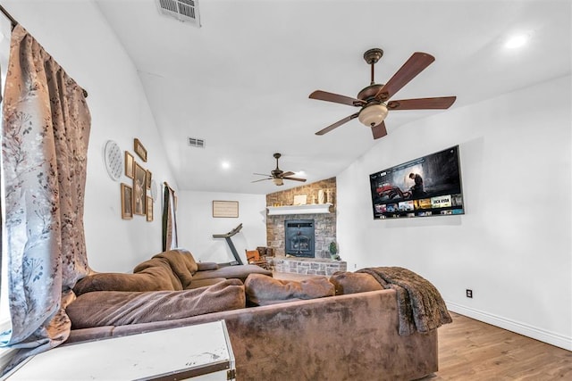 living room featuring visible vents, ceiling fan, lofted ceiling, a fireplace, and wood finished floors