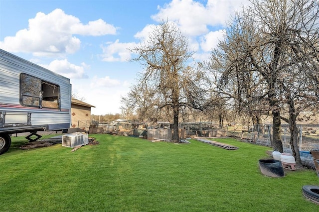 view of yard with central AC and fence