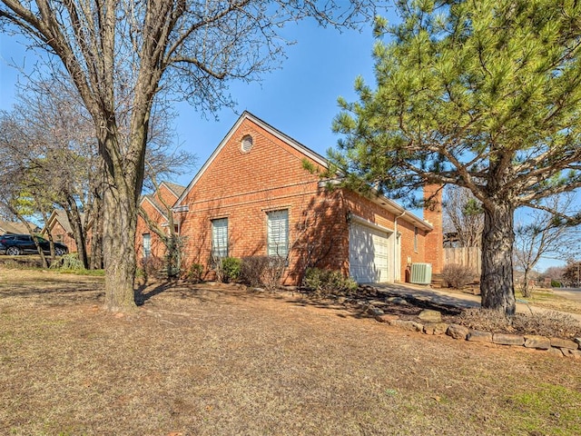 view of front of house with an attached garage, brick siding, and central AC