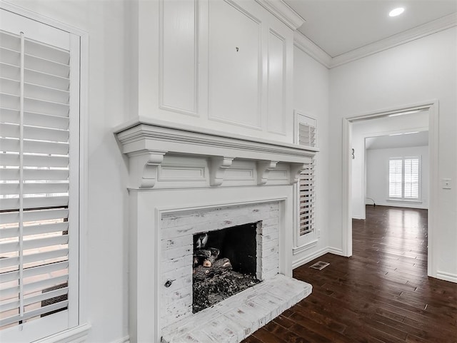 interior details featuring wood finished floors, visible vents, baseboards, a fireplace, and crown molding