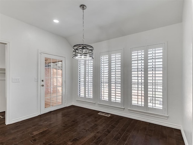 unfurnished dining area featuring visible vents, lofted ceiling, dark wood-style floors, an inviting chandelier, and baseboards