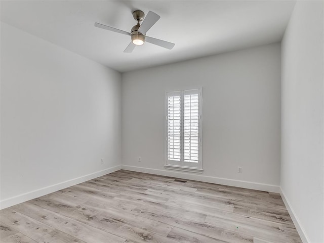 spare room with baseboards, light wood finished floors, and ceiling fan