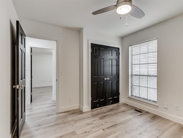 unfurnished bedroom featuring visible vents, ceiling fan, baseboards, light wood-style floors, and a closet