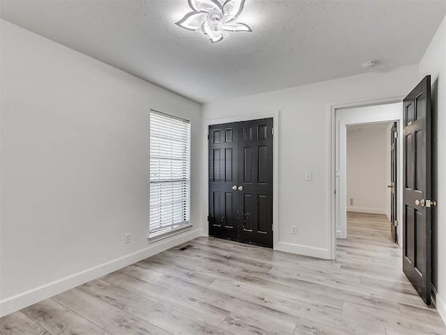 entrance foyer with light wood-type flooring, baseboards, and a textured ceiling