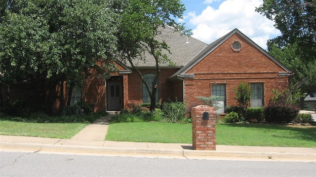 2809 Red Fern, Edmond, OK 73034 - view of front of property featuring brick siding, a front lawn, and a shingled roof