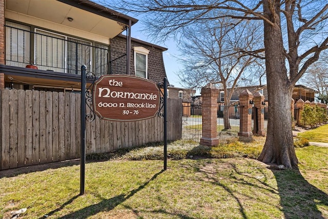 community / neighborhood sign with a yard and fence