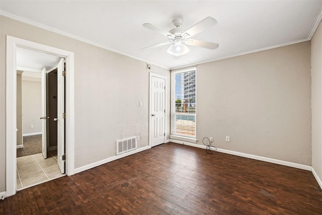 empty room featuring visible vents, ornamental molding, a ceiling fan, and wood finished floors