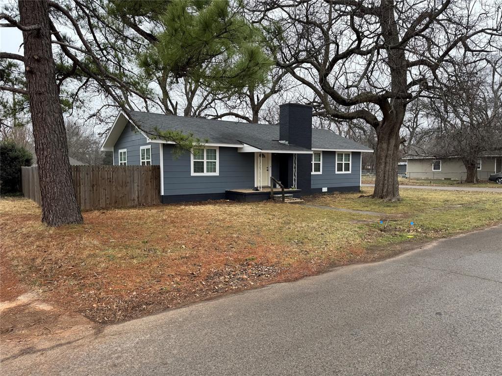 single story home featuring a chimney and fence