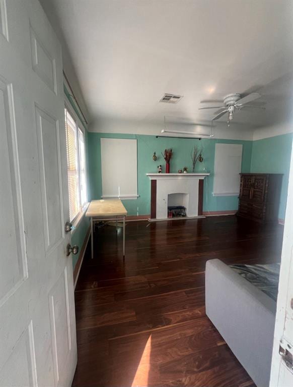 unfurnished living room with visible vents, a fireplace, wood finished floors, and a ceiling fan