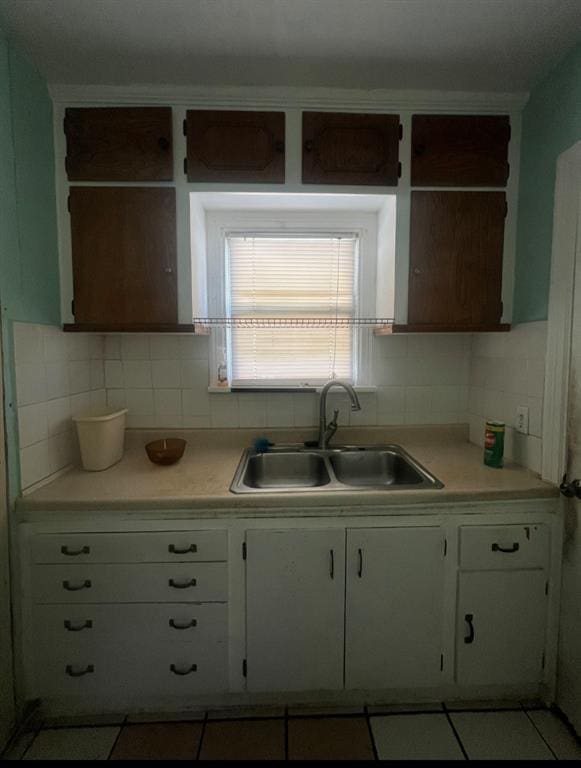 kitchen with a sink, tasteful backsplash, white cabinets, and light countertops