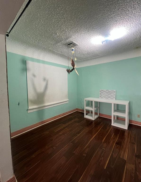 unfurnished dining area with wood finished floors, baseboards, and a textured ceiling