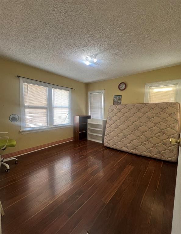 unfurnished bedroom featuring dark wood finished floors, baseboards, and a textured ceiling