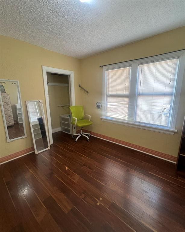 unfurnished bedroom featuring hardwood / wood-style flooring, baseboards, and a textured ceiling