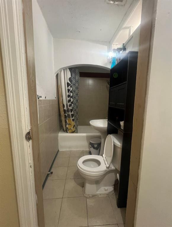 full bath with toilet, shower / tub combo, and tile patterned flooring