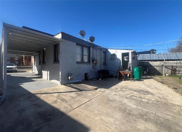 back of house featuring an attached carport, driveway, and fence