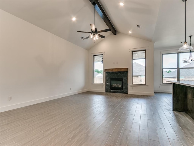 unfurnished living room with beam ceiling, light wood-style flooring, a ceiling fan, and baseboards