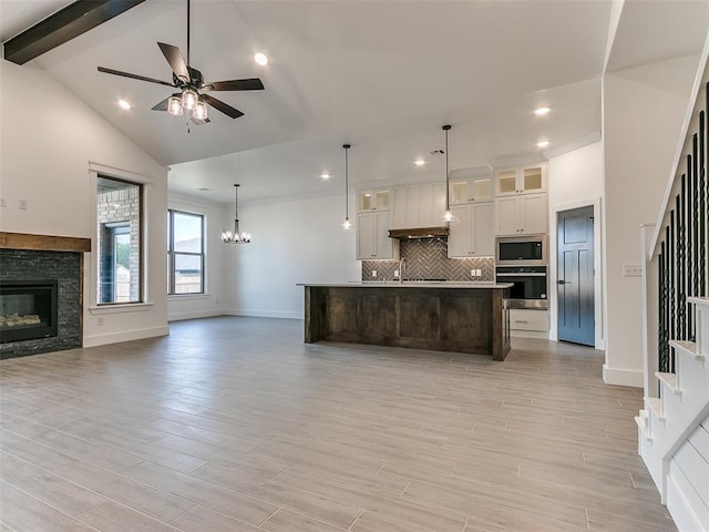 kitchen with ceiling fan with notable chandelier, open floor plan, light wood-style floors, appliances with stainless steel finishes, and decorative backsplash