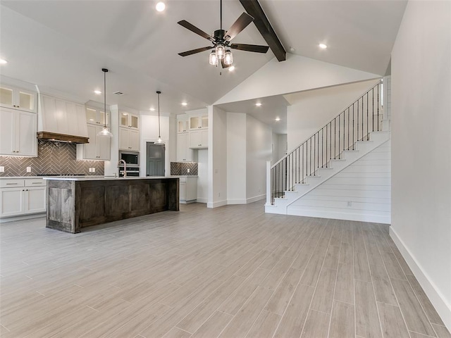 kitchen with tasteful backsplash, stainless steel microwave, light wood-style flooring, white cabinets, and a ceiling fan