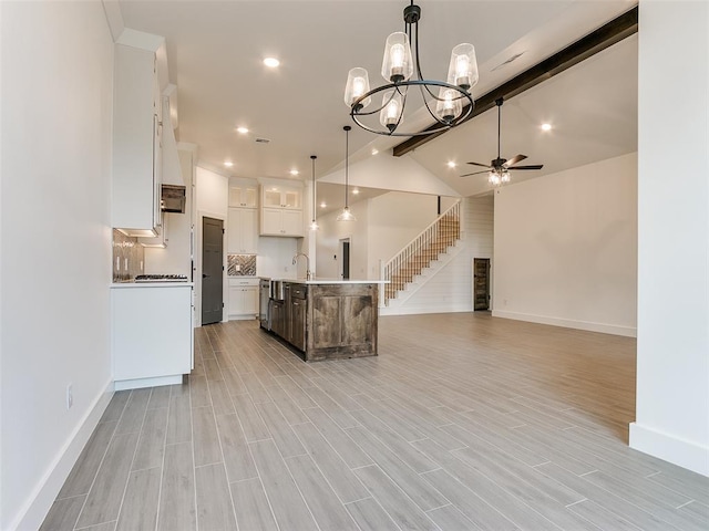 kitchen featuring wood tiled floor, lofted ceiling with beams, an island with sink, ceiling fan with notable chandelier, and open floor plan