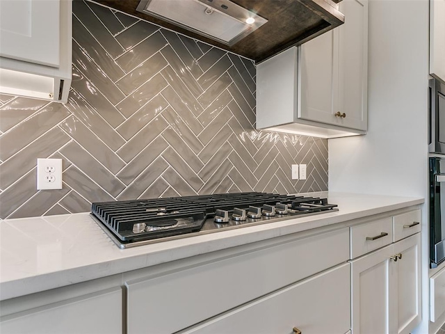 kitchen featuring tasteful backsplash, range hood, white cabinetry, stainless steel appliances, and light countertops