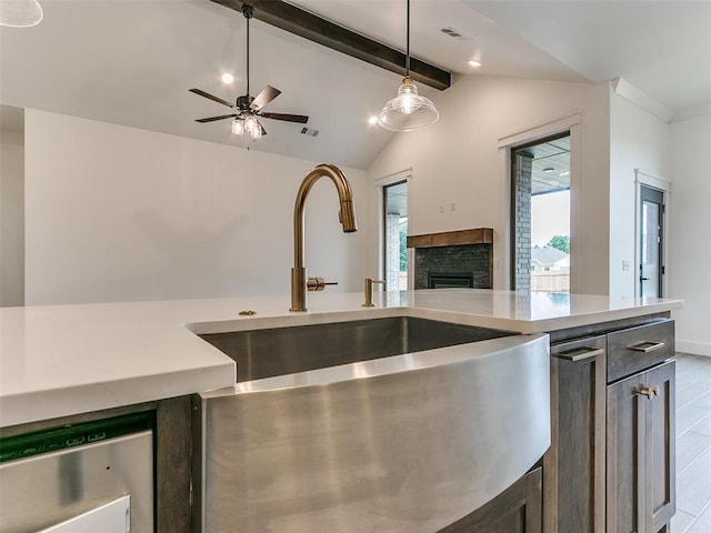 kitchen featuring visible vents, lofted ceiling with beams, ceiling fan, a stone fireplace, and light countertops