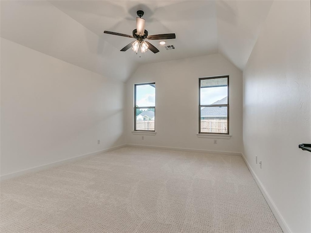 unfurnished room with visible vents, lofted ceiling, light colored carpet, and baseboards