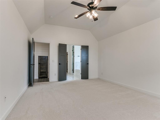 unfurnished bedroom featuring baseboards, ensuite bath, lofted ceiling, ceiling fan, and light carpet