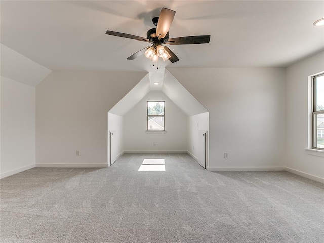 additional living space featuring baseboards, light colored carpet, ceiling fan, and vaulted ceiling