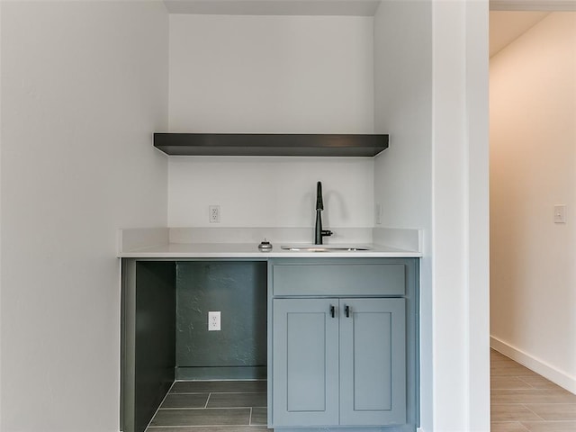 bar featuring wood tiled floor, baseboards, and a sink