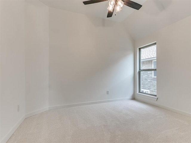 carpeted empty room with vaulted ceiling, a ceiling fan, and baseboards