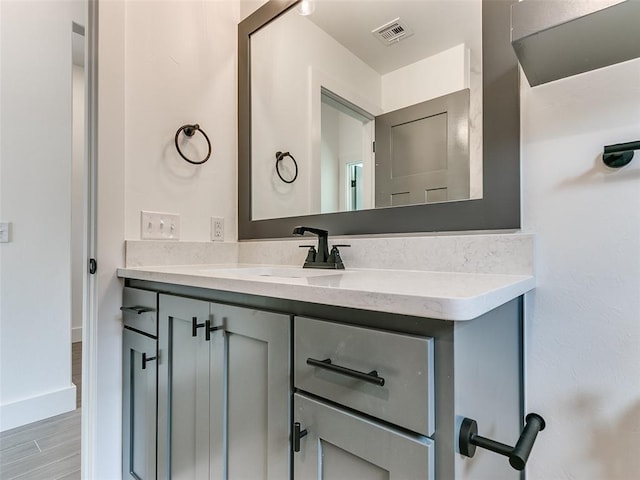 bathroom featuring visible vents, baseboards, wood finished floors, and vanity