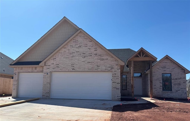 view of front of home featuring concrete driveway, an attached garage, and brick siding