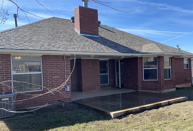 rear view of house with a chimney, brick siding, and a shingled roof