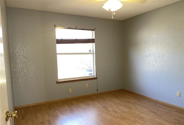 unfurnished room with plenty of natural light, light wood-style floors, baseboards, and ceiling fan