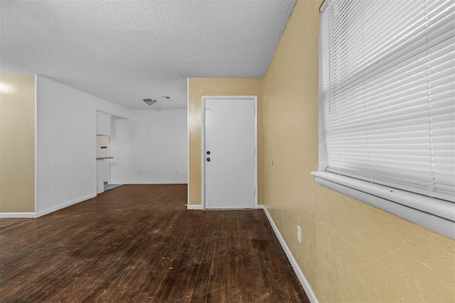 empty room featuring hardwood / wood-style flooring, baseboards, and a textured ceiling