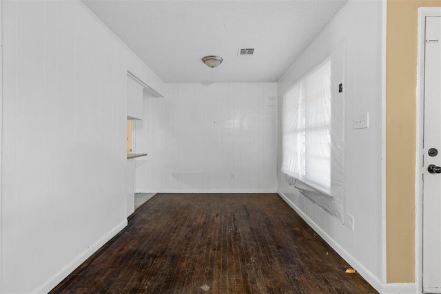 unfurnished room with baseboards, visible vents, and wood-type flooring