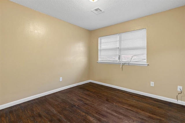 unfurnished room featuring visible vents, baseboards, and wood finished floors