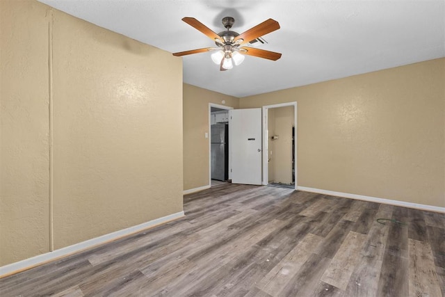 spare room with baseboards, wood finished floors, and ceiling fan